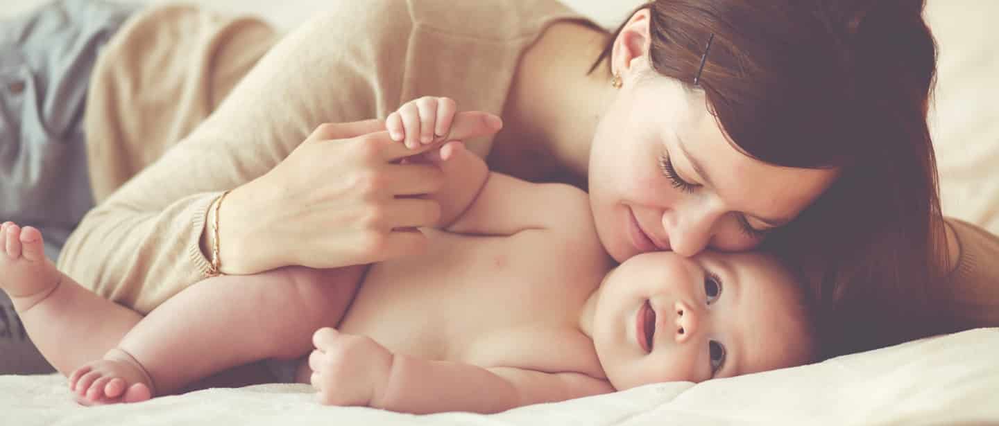 mother kissing smiling infant